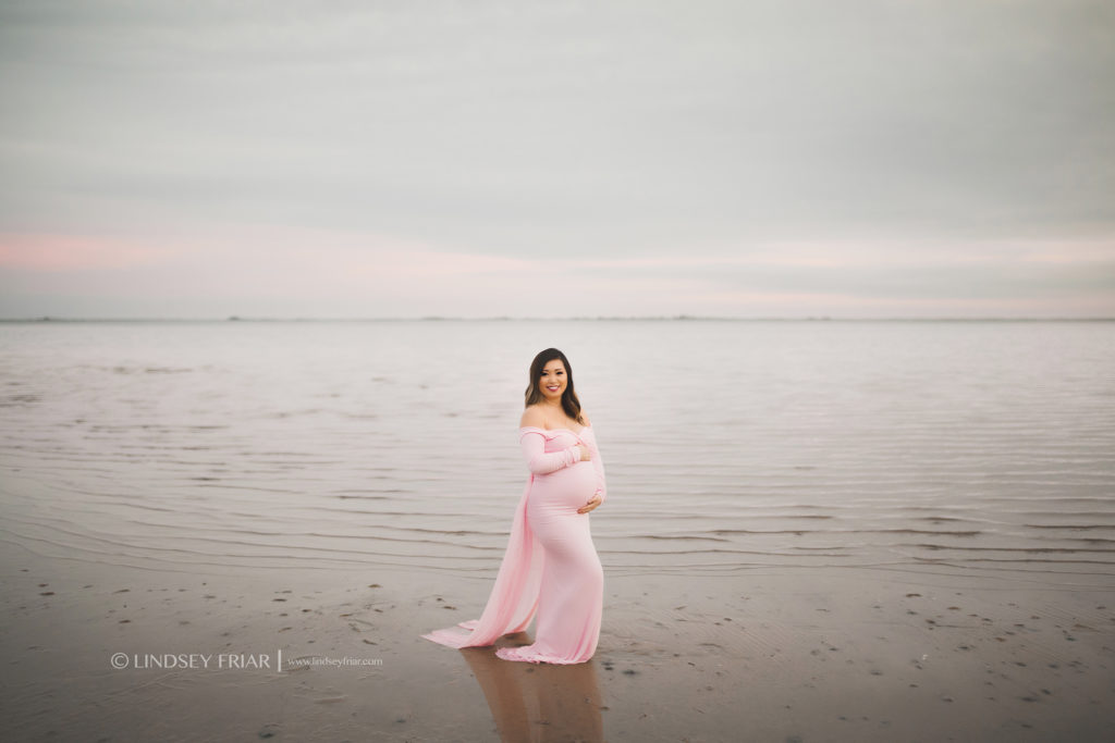 Pregnant mama standing in water wearing a long pink flowy dress