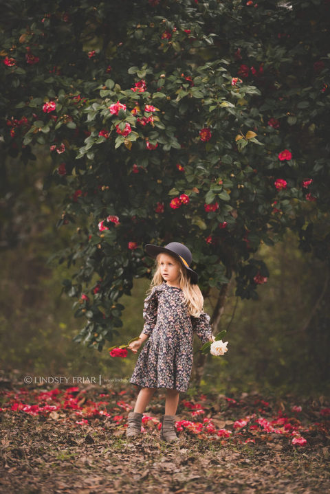girl posing in front of a camellia tree