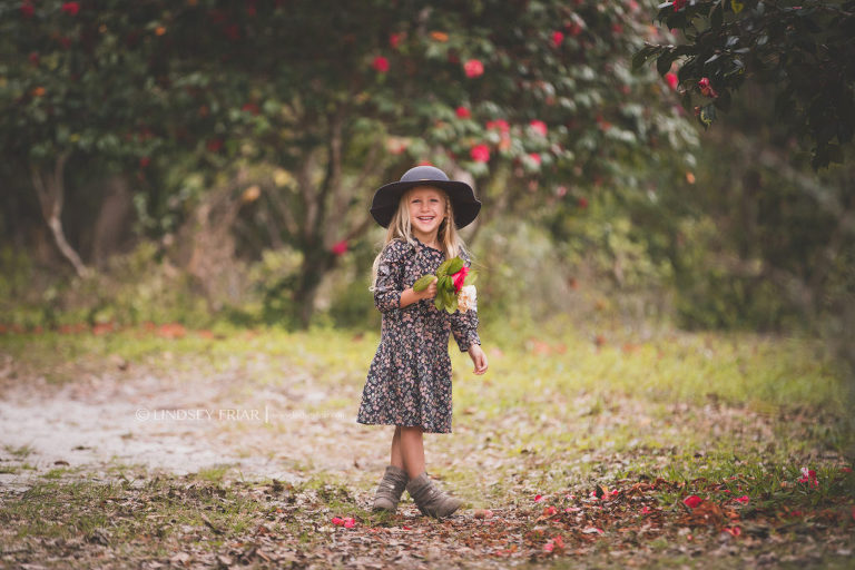 girl posing in front of blooming camellias