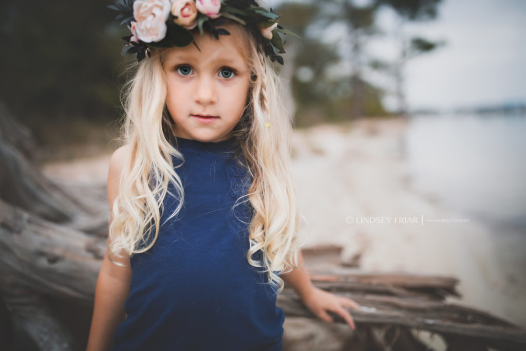 asymetrical shot of a little 4 year old girl on some driftwood