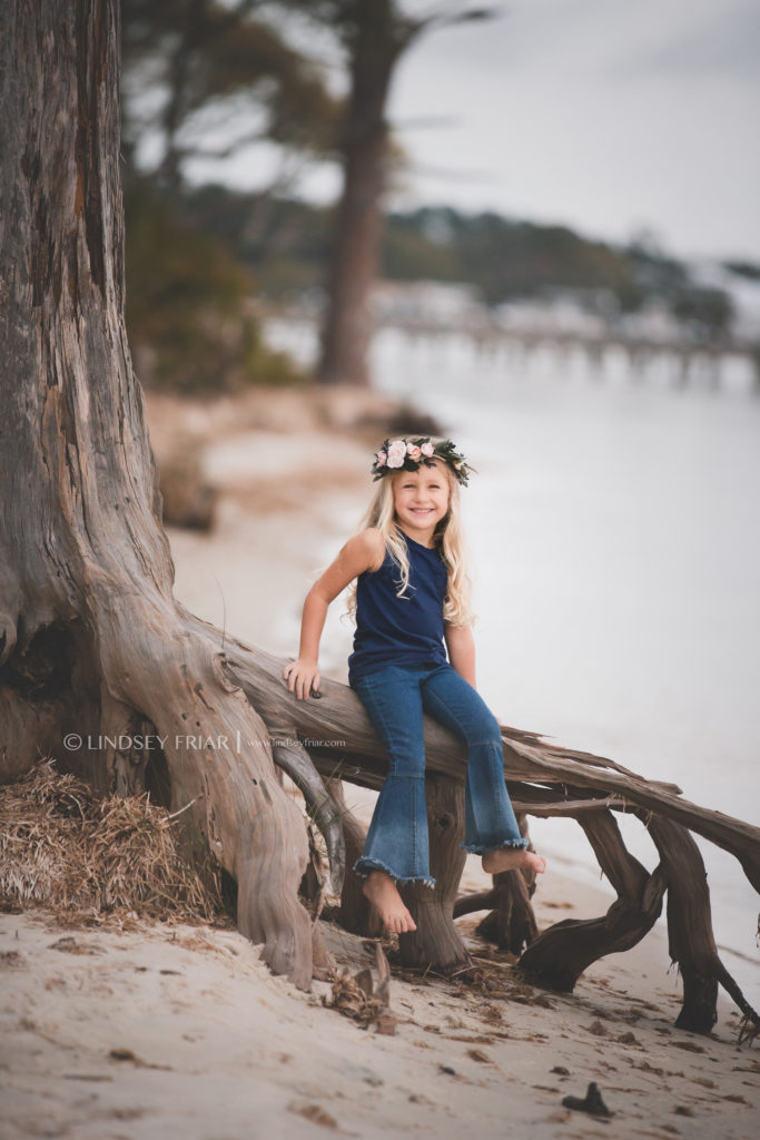 little girl sitting on drift wood