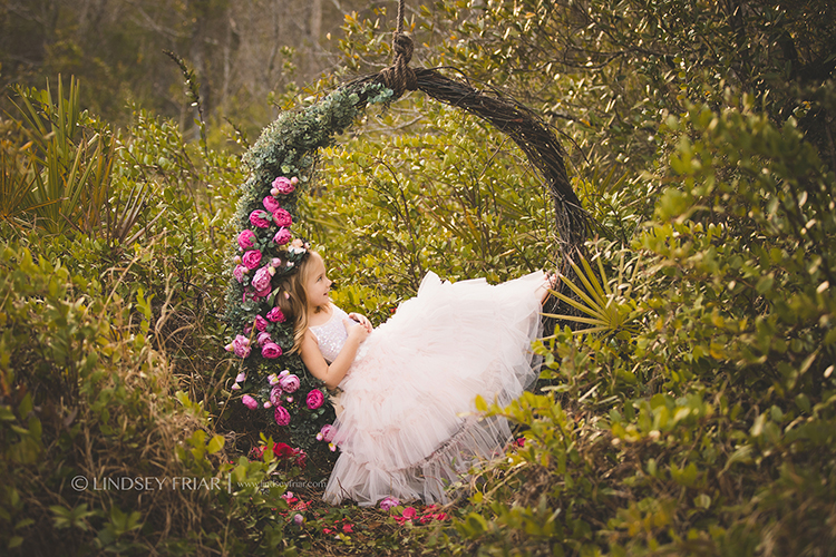 little girl laying on a garden floral swing
