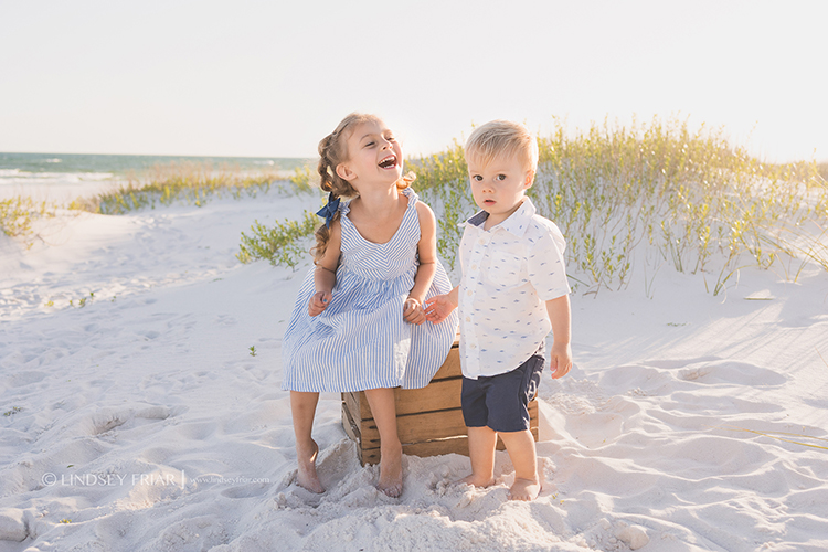 brother and sister laughing together on the beach