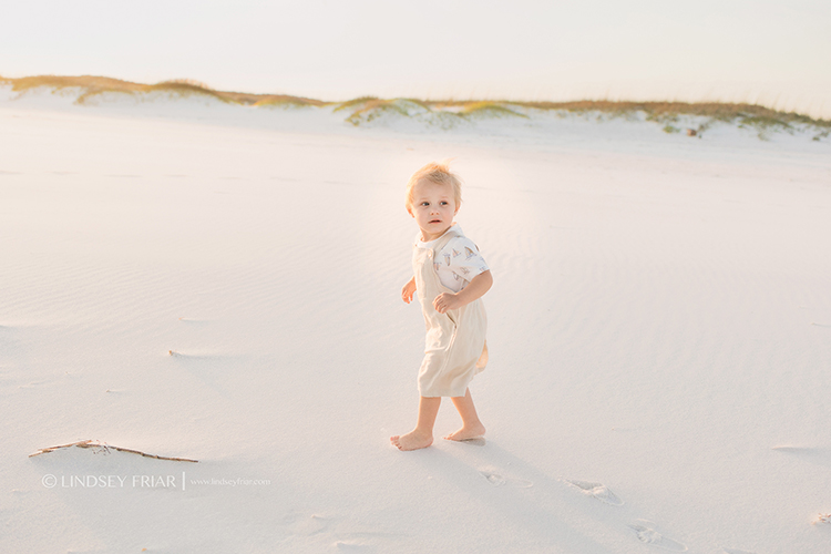 toddler looking over his shoulder on beach