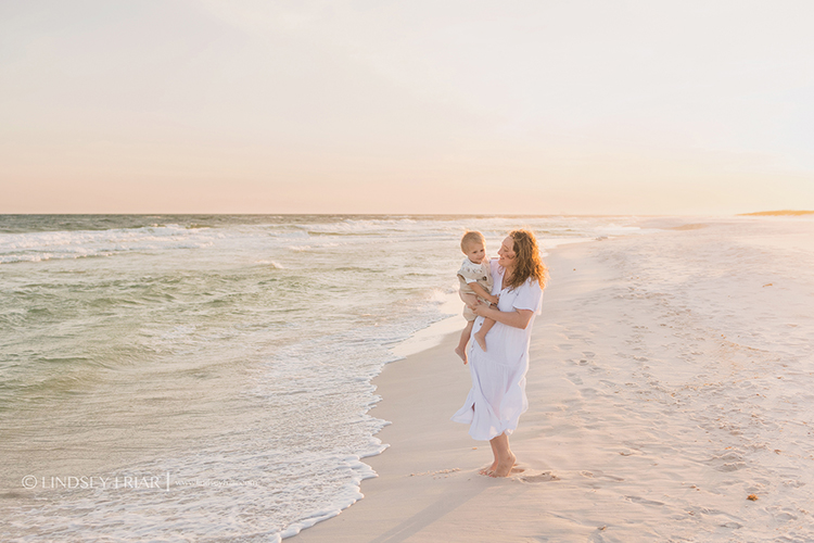 mother holding her toddler boy in front of ocean