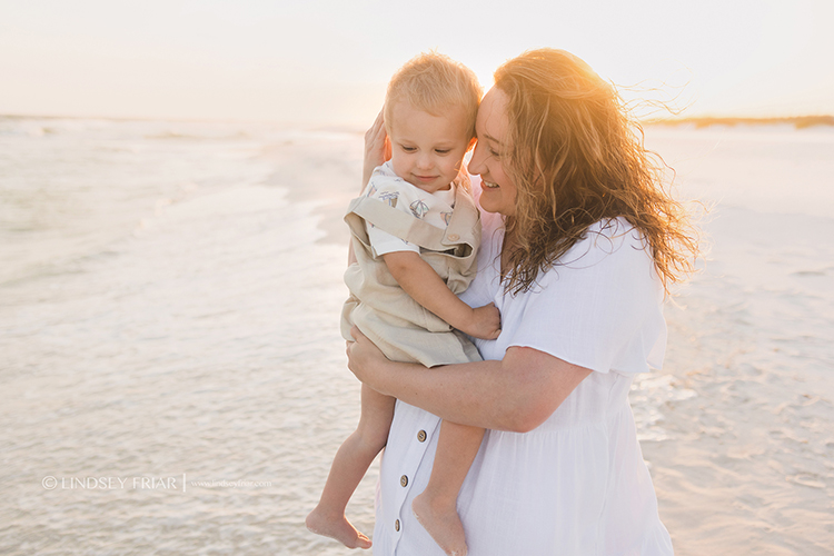 mother nestling her head on her toddlers with sunflare coming over her shoulder