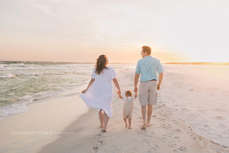 family holding hands walking into the sunset on the beach