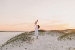 mother holding her son up in the sunset on the beach