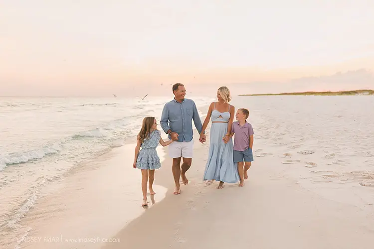 family holding hands walking on the beach