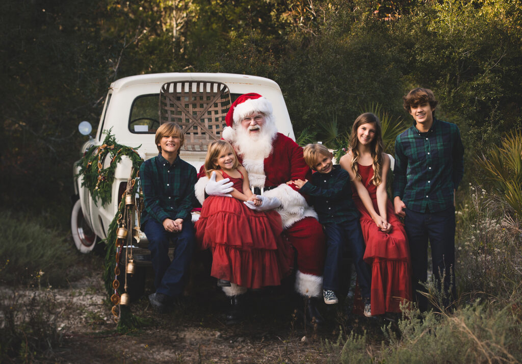 santa sitting on a white truck with 5 children